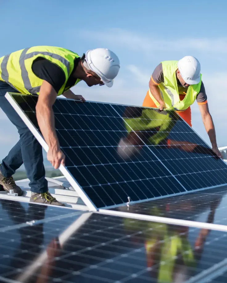 Two solar professionals reviewing a residential panel outdoors