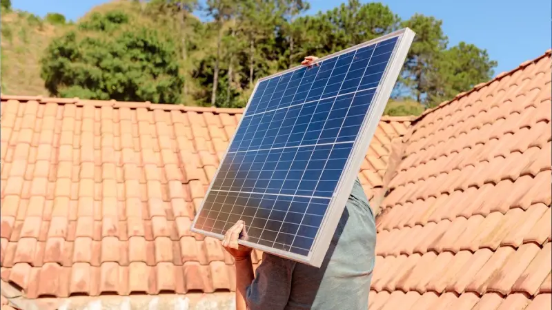 Homeowner holding a small solar panel in daylight